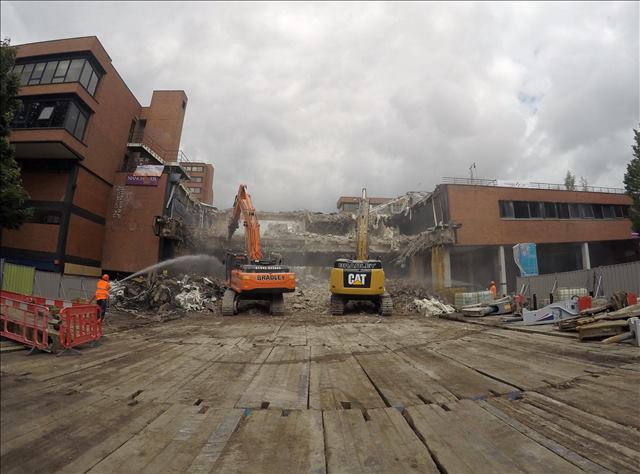 Excavators demolishing a building, with timber mats stabilising the ground at the construction site.